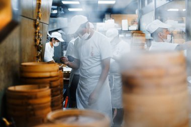 Tayvan 'ın Taipei şehrinde arka planda bulanık şeflerle birlikte restoranın önünde bambu istifleme buharı buharı gibi pişiyor..
