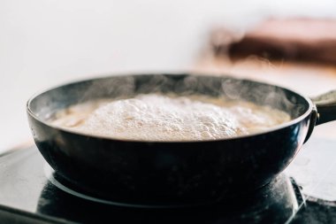 Yüzen buharlı, siyah bir tavada sıcak su. Spagetti pişirmek için kaynar su..