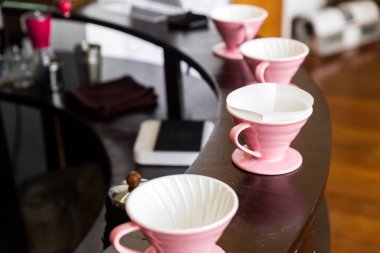 Pembe kahve öğütücüsü, kahve standı ve ahşap tezgahın üzerine damlatma adı verilen alternatif metodlu kahve yapmak için dökülmüş kahve..