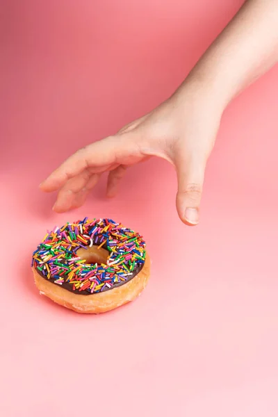 Hand Grabs Chocolate Frosted Donut Sprinkles Pink Background Playful Joyful — Stock Photo, Image