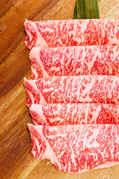 Sukiyaki ve Shabu 'ya servis edilen yüksek katmanlı ahşap tabakta az pişmiş Wagyu A5 eti..