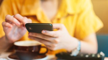 Kadın eli cep telefonuyla kafeteryadaki sosyal medyada yemek siparişini gözden geçiriyor. Modern iletişim yaşam tarzının tadını çıkar.