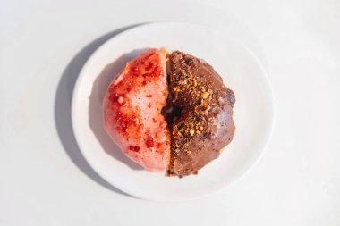 Üst görünüm (düz görünüm) yarım ev yapımı çilek pembe ve çikolata kaplı ev yapımı donut üzerine ezilmiş fındık ezmesi..