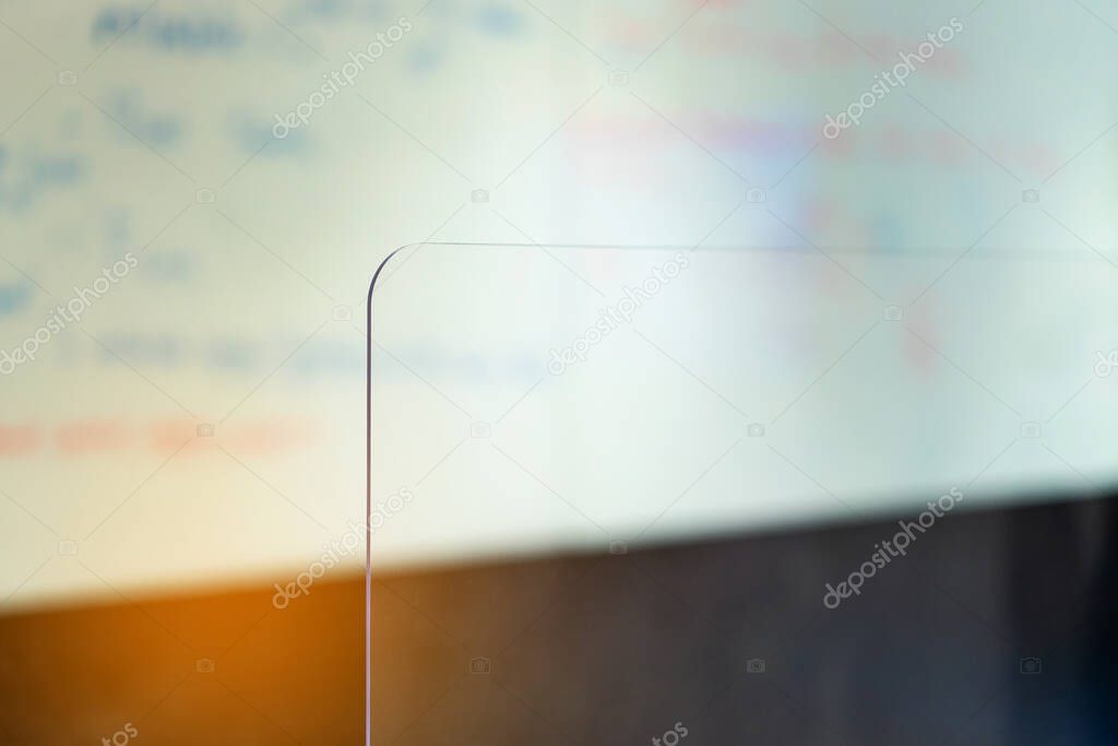 Crop image of acrylic plexiglass separator standing partition wall on the desk in the meeting room. Social distancing in offices during the Covid-19 pandemic. Precaution and safe.
