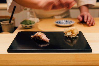 Japon Omakase yemeği: Sarı kuyruklu Amberjack Suşi, parlak siyah tabakta zencefil turşusuyla servis edilir. Japon geleneksel ve lüks yemeği.