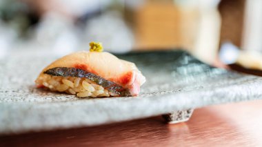 Japon Omakase yemeği: Shima Aji Sushi ve taze wasabi, taştan siyah bir tabakta elle servis edilir. Japon geleneksel ve lüks yemeği.