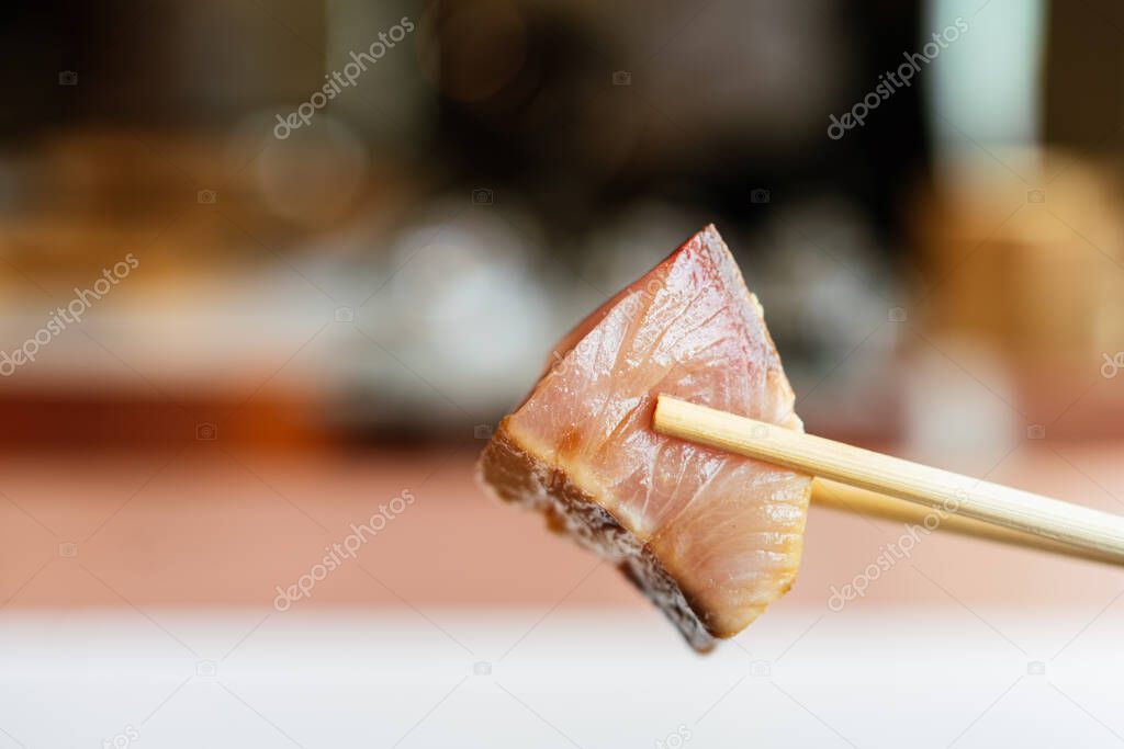Japanese Omakase meal: closed up Aged Akami Tuna (Lean Tuna) pinching with chopsticks. Japanese luxury meal.