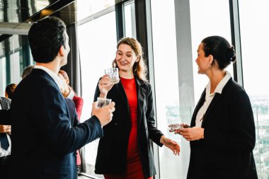 İş adamları ve yöneticiler şehir manzaralı pencerelerin yanında içki içerek şirket etkinliklerinde gülümsüyorlar. Ofis ayarları takım çalışması, toplantı, işbirliği ve meslektaşlar arasındaki bağlantıyı gösteriyor.