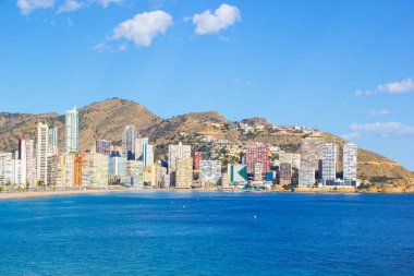 Alicante İspanya Benidorm güzel plaj, yerel Playa de Levante plaj olarak bilinen plaj, plaj ve aynı zamanda güzel bir mavi gökyüzü gününde yüksek katlı otel ve ofisler gösteren.