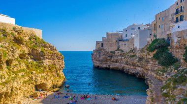 İnsanlar Blue Lagoon güneşte banyo, Polignano bir Mare plaj. Güzel berrak deniz suyunda yüzmenin havadan görünümü. Şeffaf su. Uçan drone'dan en iyi görüntü. Seyahat