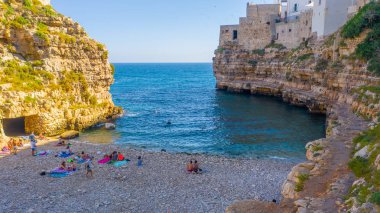 İnsanlar Blue Lagoon güneşte banyo, Polignano bir Mare plaj. Güzel berrak deniz suyunda yüzmenin havadan görünümü. Şeffaf su. Uçan drone'dan en iyi görüntü. Seyahat