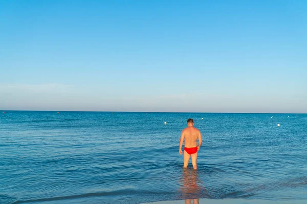 Молодой Красивый Мускулистый Мужчина Красном Купальнике Летом Пляже Входит Море — стоковое фото
