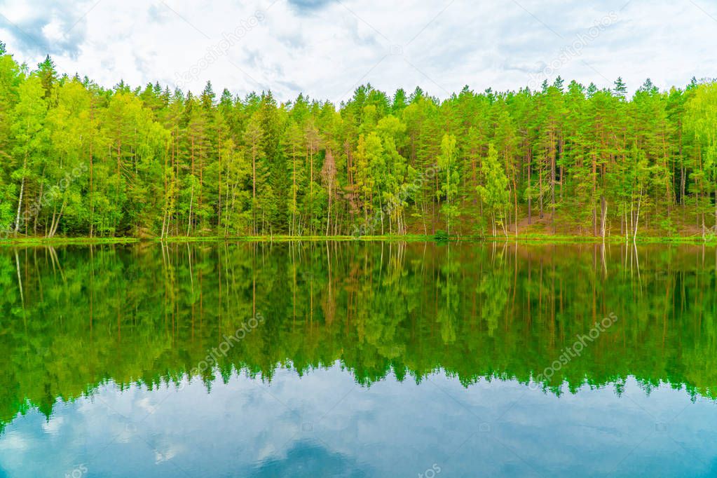 The Devil's Lake, mysterious lake in middle of forest, forest and trees are reflected in the lake water, Aglona, Latvia