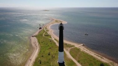 Güneşli Sorve deniz fenerinde uçan İHA 'dan güzel panoramik 4K video. Saaremaa Adası Estonya 'daki silindirik beton deniz feneri (Seriler))