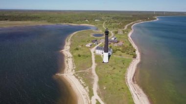 Güneşli Sorve deniz fenerinde uçan İHA 'dan güzel panoramik 4K video. Saaremaa Adası Estonya 'daki silindirik beton deniz feneri (Seriler))