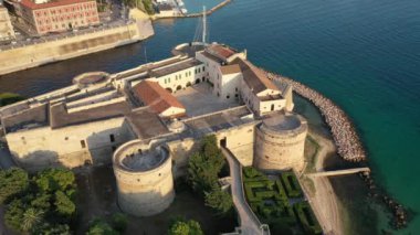 Deniz kanalındaki Eski Ortaçağ Aragonese Kalesi 'nde uçan İHA' dan güzel panoramik hava 4K videosu, günbatımında eski Taranto şehri, Puglia (Apulia), İtalya (Seriler))