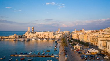 Eski Katedral San Corrado (Duomo Vecchio) ile Molfetta rıhtımında uçan İHA 'dan güzel panoramik hava manzaralı fotoğraf, gemi ve yatlarla liman ve Molfetta şehir günbatımı. Apulia, İtalya