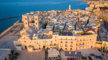 Eski Katedral San Corrado (Duomo Vecchio) ile Molfetta rıhtımında uçan İHA 'dan güzel panoramik hava manzaralı fotoğraf, gemi ve yatlarla liman ve Molfetta şehir günbatımı. Apulia, İtalya
