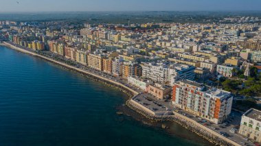 Molfetta rıhtımından ve eski kasabadan gelen güzel panoramik hava manzaralı fotoğraf. Gemileri ve yatları olan liman, Molfetta 'nın güneş doğarken yeni şehrini kapsıyor.)