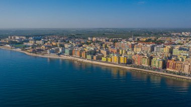 Molfetta rıhtımından ve eski kasabadan gelen güzel panoramik hava manzaralı fotoğraf. Gemileri ve yatları olan liman, Molfetta 'nın güneş doğarken yeni şehrini kapsıyor.)