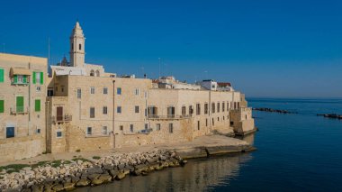 Molfetta rıhtımından ve eski kasabadan gelen güzel panoramik hava manzaralı fotoğraf. Gemileri ve yatları olan liman, Molfetta 'nın güneş doğarken yeni şehrini kapsıyor.)