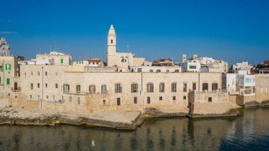 Molfetta rıhtımından ve eski kasabadan gelen güzel panoramik hava manzaralı fotoğraf. Gemileri ve yatları olan liman, Molfetta 'nın güneş doğarken yeni şehrini kapsıyor.)