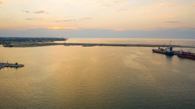 Molfetta limanındaki deniz fenerinde uçan İHA 'dan güzel panoramik hava manzaralı fotoğraf. Günbatımında gemiler, liman, yat kumu ve Molfetta şehriyle arka planda.)