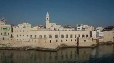 Molfetta rıhtımında ve büyük bir yükseklikten eski kentte uçan İHA 'nın güzel panoramik hava 4K videosu. Gemileri ve yatları olan liman, Molfetta' nın güneşte yeni şehrini kapsıyor.)