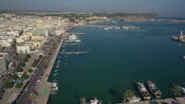 Molfetta rıhtımında ve büyük bir yükseklikten eski kentte uçan İHA 'nın güzel panoramik hava 4K videosu. Gemileri ve yatları olan liman, Molfetta' nın güneşte yeni şehrini kapsıyor.)
