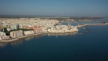 Molfetta rıhtımında ve büyük bir yükseklikten eski kentte uçan İHA 'nın güzel panoramik hava 4K videosu. Gemileri ve yatları olan liman, Molfetta' nın güneşte yeni şehrini kapsıyor.)