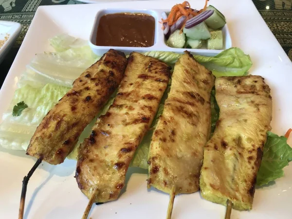 A plate of BBQ chicken on the sticks.