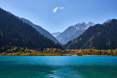 Sonbaharda Kazakistan 'ın Alatau dağlarında, dağların yamaçlarında ve dağların tepesinde kar olan Issyk Gölü.
