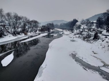 Kış mevsiminde kar ve buz ile donmuş nehir. Romanya, Transilvanya, Nasaud şehri. Kış manzarası