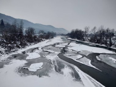 Kış mevsiminde kar ve buz ile donmuş nehir. Romanya, Transilvanya, Nasaud şehri. Kış manzarası