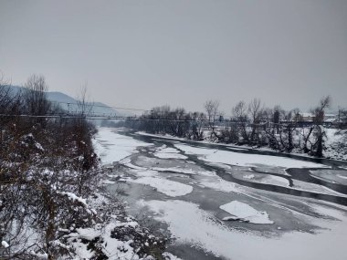 Kış mevsiminde kar ve buz ile donmuş nehir. Romanya, Transilvanya, Nasaud şehri. Kış manzarası
