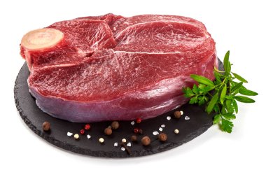 Taş tabakta biftek için kemikli taze çiğ et, beyaz arka planda izole edilmiş.