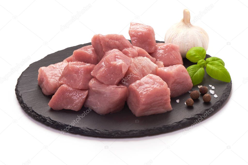 Raw pork pieces on stone plate, close-up, isolated on white background.