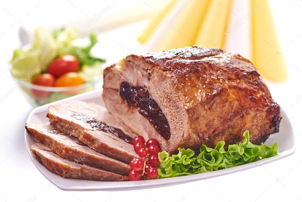 Roast pork with prunes on blurred background, close-up.