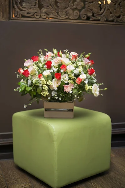 Ramo de flores en una caja de madera cuesta en un taburete acolchado verde — Foto de Stock