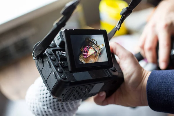 cake photo on the camera screen. the girl holds the camera in hand.