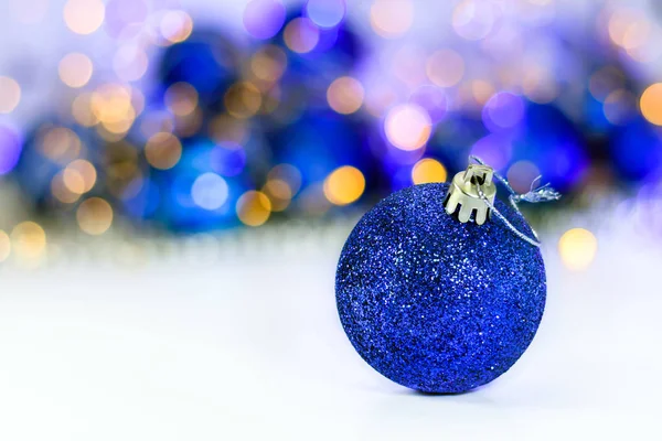 Blue glitter Christmas ball on abstract light background.