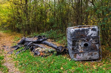 Terk edilmiş kimyasal plastik tankın içinde Doğa Sonbahar yaprakları ile kaplı. Çevre kirliliği.