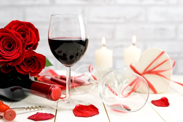 情人节晚餐的概念 两杯葡萄酒 红玫瑰 软木塞 礼品盒 盘子和燃烧的蜡烛在一个白色的木制桌子上 有选择的重点 — 图库照片