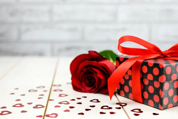 Red rose, gift box and small hearts on white wooden table with copy space for text. Valentine's Day and Mother's Day card concept.