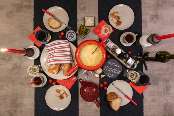 Geleneksel İsviçre peyniri fondü beton yemek masası üzerinde kırmızı bir tencerede.