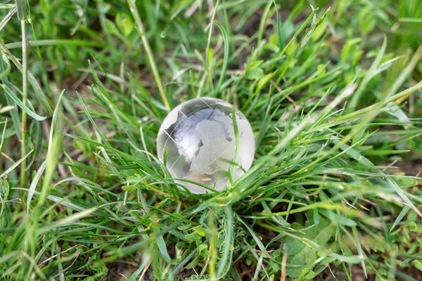 The concept of ecology and a safe environment. Glass ball, globe on a background of green grass