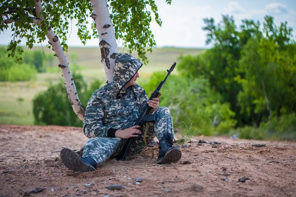 穿着伪装制服的男子坐在沙漠里的一棵树下 — 图库照片
