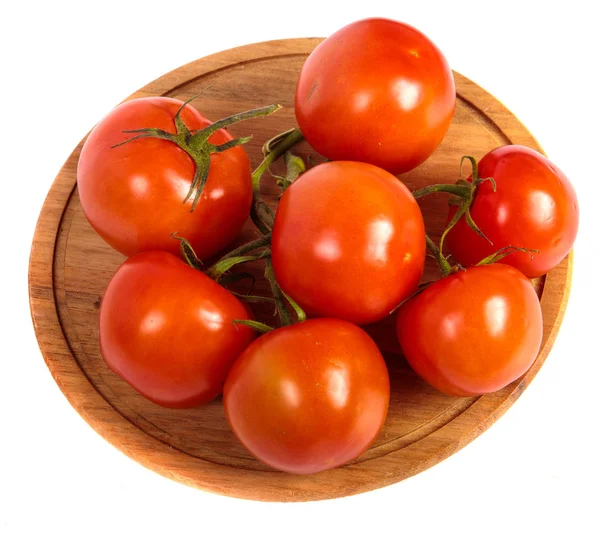 Rijpe rode tomaten op een ronde houten snijplank. witte blauw — Stockfoto