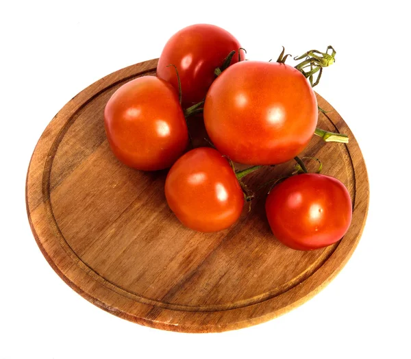 Tomates vermelhos maduros em uma tábua de corte de madeira redonda. backgro branco — Fotografia de Stock