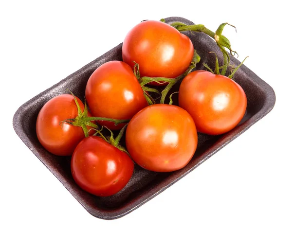 Tomates vermelhos maduros em uma bandeja de plástico escuro. sobre um fundo branco — Fotografia de Stock
